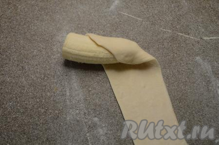 Очистить банан, разрезать на 2 примерно равные части. Начиная с узкого края банана, начать заворачивать банан в раскатанную полоску теста, как на фото.