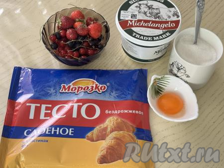 Подготовить продукты для приготовления слоек с рикоттой и ягодами. Слоёное тесто можно взять как дрожжевое, так и бездрожжевое, его нужно разморозить при комнатной температуре. У меня было бездрожжевое слоёное тесто. Ягоды можно взять любые свежие или замороженные. Я взяла свежие ягоды: чёрную и красную смородину, а также малину и клубнику. Свежие ягоды нужно промыть водой, убирая веточки, обсушить. Если ягоды с крупными косточками (например, черешня или вишня), тогда косточки  нужно удалить. Если будете использовать замороженные ягоды, на которых нет большого количества льда, значит их можно не размораживать. 