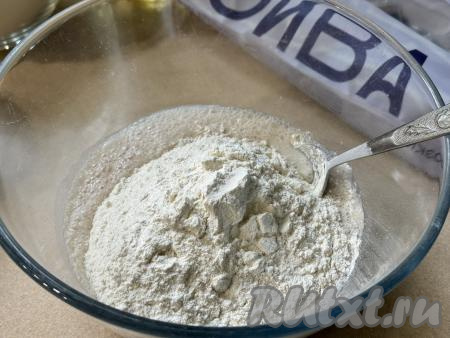 Затем всыпать в миску половину муки, перемешать столовой ложкой.