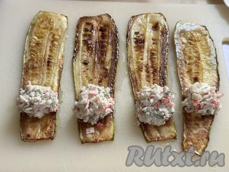 На более узкую часть полоски из кабачка, немного отступив от края, выложить 1 чайную ложку начинки. 