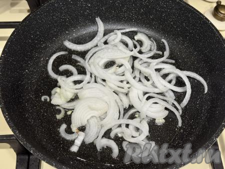 Лук, чеснок и морковь почистить. Кабачок для этого блюда нужно брать молодой, то есть с мелкими семечками и тонкой кожурой. Тонкую кожуру с кабачка можно не срезать. Кабачок и свежую зелень (у меня - кинза, можно взять петрушку) вымыть. В сковороду влить растительное масло, разогреть, выложить лук, нарезанный на полукольца. Обжарить лук до прозрачности (в течение 5-6 минут), иногда помешивая, на среднем огне. 
