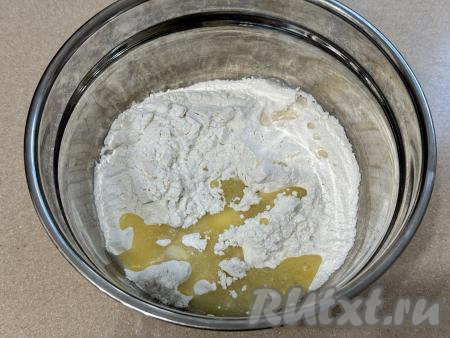 Влить в миску с мукой всё остывшее растопленное масло и 1 столовую ложку воды.