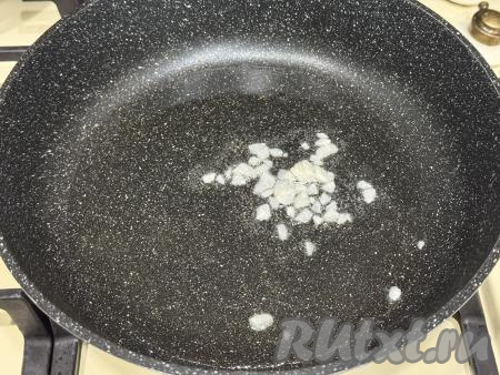 В сковороду влить растительное масло, разогреть, выложить очищенные и мелко нарезанные зубчики чеснока, обжарить на среднем огне 1 минуту, периодически перемешивая. 