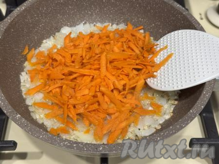 К обжаренному луку выложить натёртую на крупной тёрке морковку, перемешать и обжаривать минут 5-7 (до мягкости моркови), время от времени перемешивая.