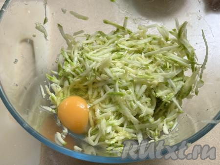 Кабачковую массу, отжатую от лишнего сока, выложить в объёмную миску, добавить яйцо, перемешать столовой ложкой до однородности. 