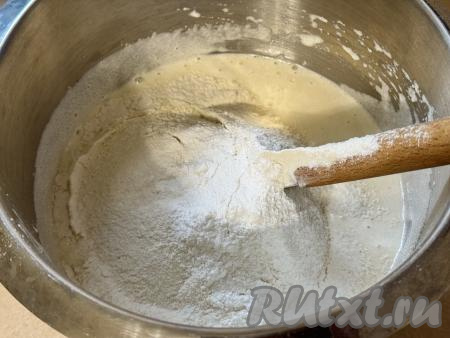 В получившуюся массу всыпать половину стакана просеянной муки и весь разрыхлитель, перемешать тесто лопаткой. 