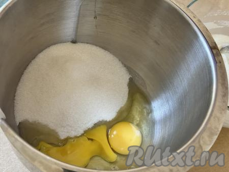 По прошествии 30 минут в чашу миксера (или глубокую ёмкость, в которой вам будет удобно взбивать миксером) всыпать сахар, вбить сырые яйца. 