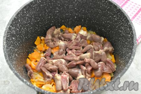 Пока обжариваются овощи разрезаем куриные сердечки пополам, тщательно промываем их, удаляя сгустки крови. После того как морковка обжарится 4-5 минут, выкладываем к овощам куриные сердечки, перемешиваем, обжариваем 7-8 минут.