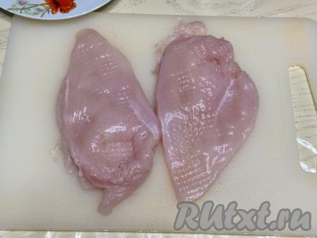 Куриное филе выложить на разделочную доску, накрыть мясо плёнкой и отбить с двух сторон не очень тонко (до толщины примерно 1 сантиметр).