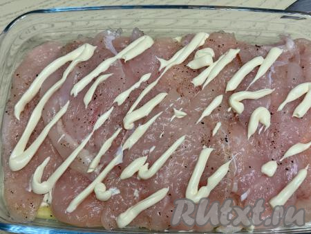 Выложить отбитые кусочки мяса курицы поверх картошки, нанести сетку из майонеза. 
