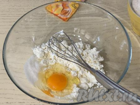 В достаточно глубокую миску выложить творог, размять вилкой, добавить яйцо и сахар. 