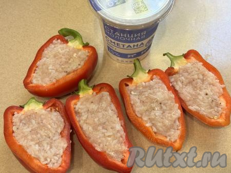 Так как перцы мы будем готовить с плодоножкой, каждый болгарский перец нужно тщательно промыть снаружи. Затем разрезать перцы на две половинки, удалить семечки и крупные перегородки, снова промыть водой. Выложить начинку из фарша и риса в половинки перца. 