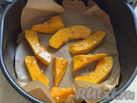 Дно чаши аэрогриля выстелить пергаментом. Выложить кусочки тыквы в чашу аэрогриля в один слой.