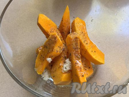 Выложить тыкву в миску, добавить пропущенный через пресс чеснок, соль и чёрный молотый перец, влить растительное масло. Хорошо перемешать, покрывая тыкву специями и маслом со всех сторон.