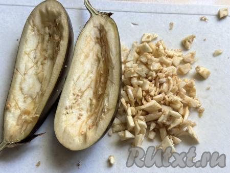 Сделать на мякоти баклажанов крестообразные надрезы ножом, чтобы легче было вынимать мякоть. А затем удалить часть мякоти из баклажана, сформировав бортики лодочки. Вынутую из баклажанов мякоть мелко нарезать.