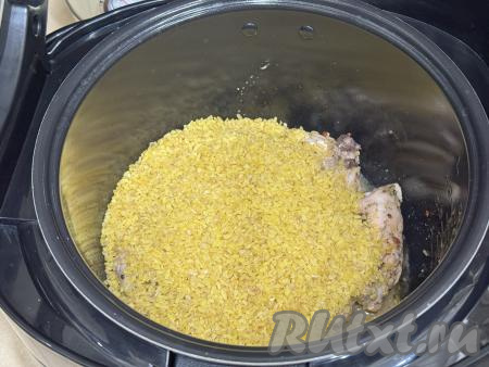Затем к обжаренным куриным бёдрам всыпать булгур (предварительно промывать его не нужно).
