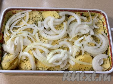 Поверх картошки разложить лук, нарезанный полукольцами. 