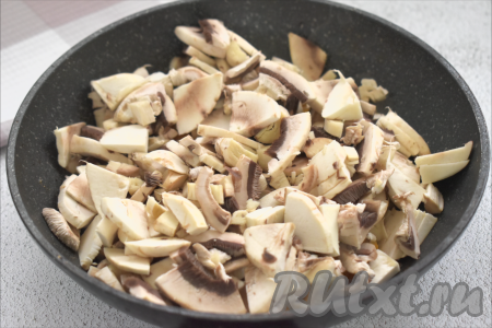 Пока обжариваются овощи, шампиньоны моем, немного обсушиваем, нарезаем на ломтики. После того как морковь станет достаточно мягкой, выкладываем в сковороду нарезанные грибы, перемешиваем. Обжариваем овощи с шампиньонами минут 7, периодически перемешивая.