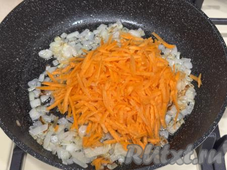 К обжаренному луку выложить натёртую на крупной тёрке морковку.
