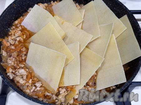 Выложить листы для лазаньи в фарш, как бы утапливая листы в закипевший соус.