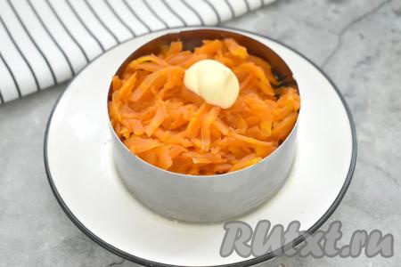 Третьим слоем раскладываем по кольцам морковь, натёртую на крупной тёрке, слегка утрамбовываем, покрываем майонезом.