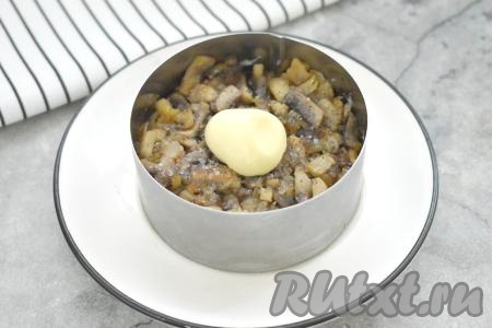 Вторым слоем по двум кольцам раскладываем обжаренные шампиньоны с луком, немного утрамбовываем, затем немного солим и перчим. Смазываем грибной слой майонезом.