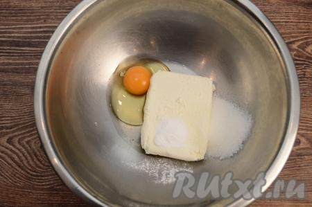 По прошествии 5 минут слить воду с изюма, разложить его на бумажном полотенце, чтобы избавиться от воды. Осмотреть изюм, удаляя, если они есть, мелкие веточки. Пока изюм обсыхает, нужно в глубокую миску выложить творог, вбить яйцо, всыпать сахар и разрыхлитель. 