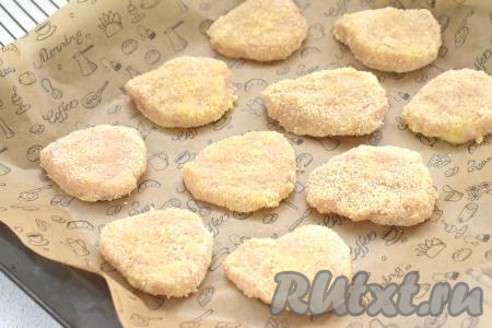 Наггетсы из куриного фарша в панировке выкладываем на противень, застеленный пергаментом (или ковриком) для выпечки, отправляем в духовку, разогретую до 190 градусов, на 20 минут.