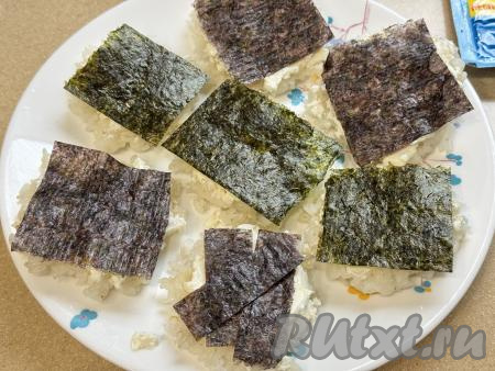 Нарезать листы нори по размеру заготовок и выложить поверх творожного сыра.