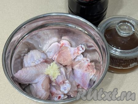 Выложить куриные крылышки в миску, добавить пропущенный через пресс чеснок.