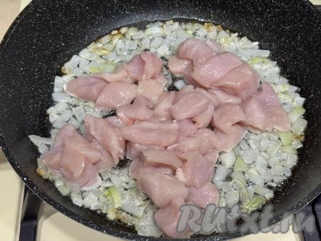 Обжарить лук на среднем огне до прозрачности (в течение 3-4 минут), иногда помешивая. После того как лук станет прозрачным, добавить к нему куриное мясо, нарезанное на средние кусочки, перемешать. 