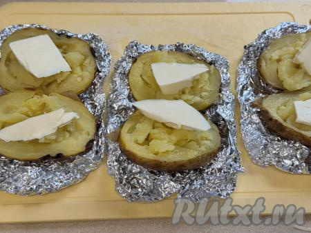 Готовый запечённый картофель, достать из аэрогриля, развернуть фольгу. С фольги картошку убирать не нужно. Разрезать каждую картошину вдоль на 2 части.  Вилкой размять мякоть картошки. Сверху на каждую половинку картошки выложить небольшой кусочек сливочного масла.