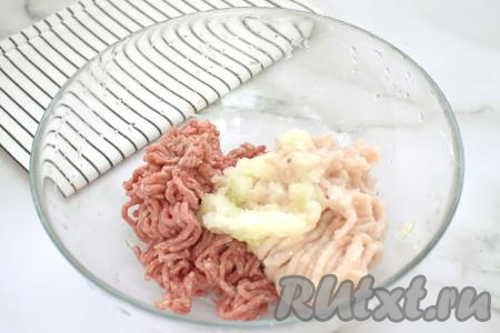 В миску выкладываем говяжий фарш, добавляем куриный фарш. Сюда же выкладываем натёртый на крупной тёрке (или пропущенный через мясорубку) лук. Безусловно, можно лук и нарезать мелко, но котлеты получатся менее нежными.