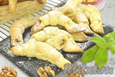 Достаём противень с выпечкой из духовки. Ароматные, аппетитные рогалики с грецкими орехами, приготовленные из слоёного теста, станут прекрасным дополнением к чашечке горячего чая или кофе. 