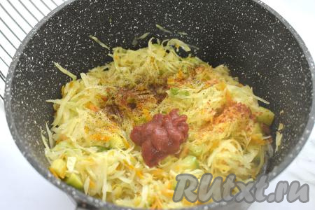 После того как капуста обмякнет, добавляем к овощам томатную пасту и специи (у меня - чёрный молотый перец и паприка). Солить пока не нужно, ведь капусту до этого мы уже присаливали. Вливаем 150 миллилитров воды, перемешиваем. Даём получившему томатному соусу закипеть, уменьшаем огонь. Тушим капусту с кабачками под крышкой в томатном соусе 10-15 минут. В процессе тушения овощи нужно будет 2-3 раза перемешать.