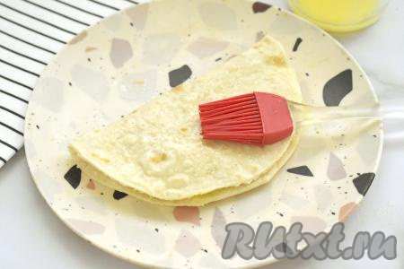 Сторону с начинкой накрываем свободной стороной лепёшки, немного прижимаем сверху. У нас получится кыстыбый с начинкой из картошки и сыра. Сразу горячий кыстыбый с двух сторон щедро смазываем растопленным сливочным маслом (я заранее растопила масло в микроволновке в течение 20 секунд). Благодаря смазыванию маслом, кыстыбый станет мягким, нежным. Постепенно выпекаем все лепёшки, выкладываем на них картофельно-сырную начинку, горячими смазываем их растопленным сливочным маслом с двух сторон.