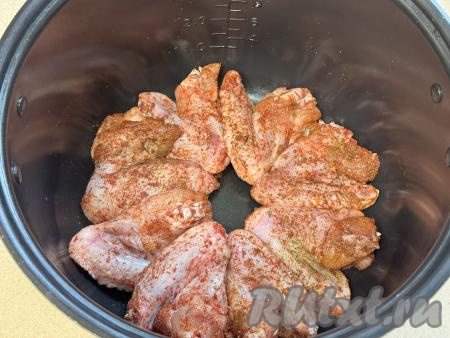 По прошествии 30 минут куриные крылья, промариновавшиеся в специях, выложить в один слой в чашу мультиварки. 