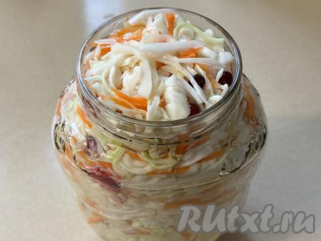 Переложить капусту с яблоком, клюквой и морковью в чистую 2-х литровую банку, плотно утрамбовывая. Сразу влить в банку 200 миллилитров фильтрованной (или остывшей кипячёной) воды. 
