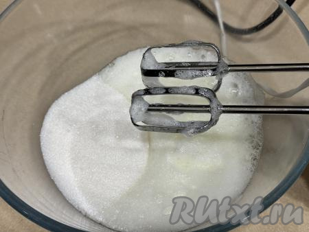 Пока пирог запекается в духовке, сразу займёмся безе. Яичные белки нужно достать из холодильника, поместить в абсолютно сухую ёмкость, удобную для взбивания. Белки взбить миксером на максимальных оборотах до пышного состояния, а затем, не прекращая взбивать, добавить небольшими частями сахар.