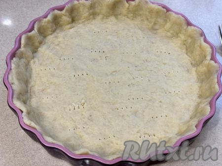 Выложить тесто в круглую форму для выпечки (я использовала форму диаметром 26 сантиметров). Распределить тесто по форме, сформировав невысокий бортик. Тесто на дне формы наколоть вилкой (благодаря накалыванию, тесто не будет сильно подниматься в процессе выпечки). Форму с тестом поставить в разогретую до 180 духовку, запекать 10 минут.