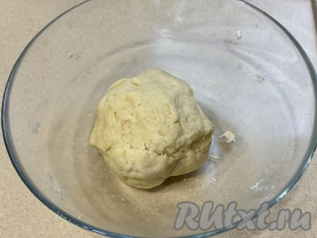 Замесить руками пластичное и нежное песочное тесто, которое будет чуть липнуть к рукам. Как только тесто соберётся в ком, значит больше вымешивать его не нужно. Если тесто будет плохо собираться в ком, тогда можно влить 0,5-1 столовую ложку холодной воды, собирая тесто в ком.