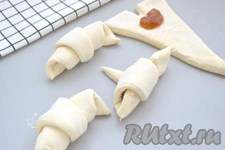 Начиная со стороны с надрезом, аккуратно сворачиваем треугольник из слоёного теста в рогалик. Хвостик получившегося рогалика должен быть снизу. Постепенно формируем все 4  круассана с повидлом.