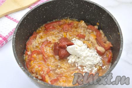 Затем к тушёнке с овощами всыпаем муку, добавляем томатную пасту, по вкусу солим и перчим, перемешиваем, тушим 1 минуту.