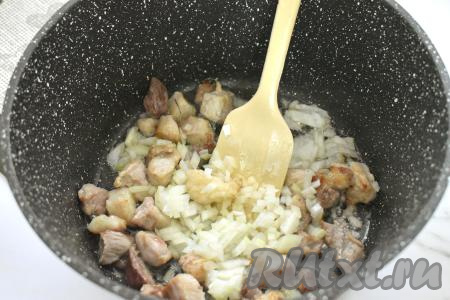 К обжаренной свинине выкладываем мелко нарезанный лук, перемешиваем, обжариваем на среднем огне, иногда помешивая, минуты 3-4.