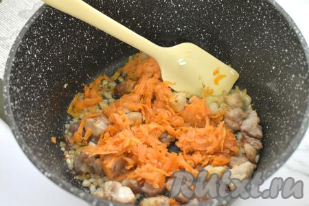 К свинине, обжаренной с луком, добавляем морковку, натёртую на крупной тёрке, перемешиваем. Обжариваем мясо с овощами 5 минут, время от времени перемешиваем. 