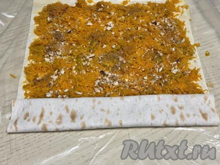 Начиная с более узкой стороны лаваша, свернуть лаваш с начинкой из тыквы в плоский рулет. 