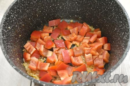 Пока лук обжаривается, очищаем болгарский перец от семян и плодоножки. Промываем перец водой, затем нарезаем на небольшие кубики. К луку, обжаренному до прозрачности, выкладываем болгарский перец, перемешиваем овощи. Обжариваем минуты 3-4, время от времени помешивая.