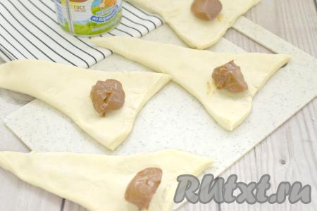 Ближе к основанию заготовок, отступая от краёв теста по 1-1,5 сантиметру, выкладываем по 1 чайной ложке варёной сгущёнки.