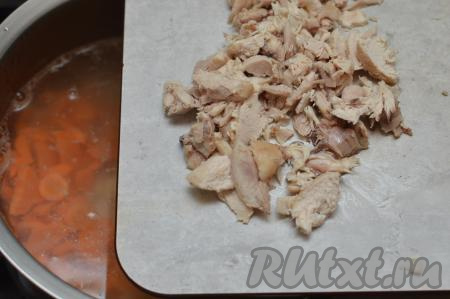 Остывшие части курицы отделить от костей, нарезать на кусочки, добавить в суп следом за морковью.