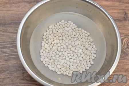 Для того чтобы сухая фасоль сварилась быстрее, желательно замочить её с вечера. Для этого нужно взять 190 грамм сухой фасоли (это примерно 1 стакан объёмом 200 миллилитров), выложить в сито, хорошо промыть проточной водой, лишней воде дать стечь. Промытую фасоль выложить в глубокую миску, залить достаточно большим количеством воды и оставить на ночь. 